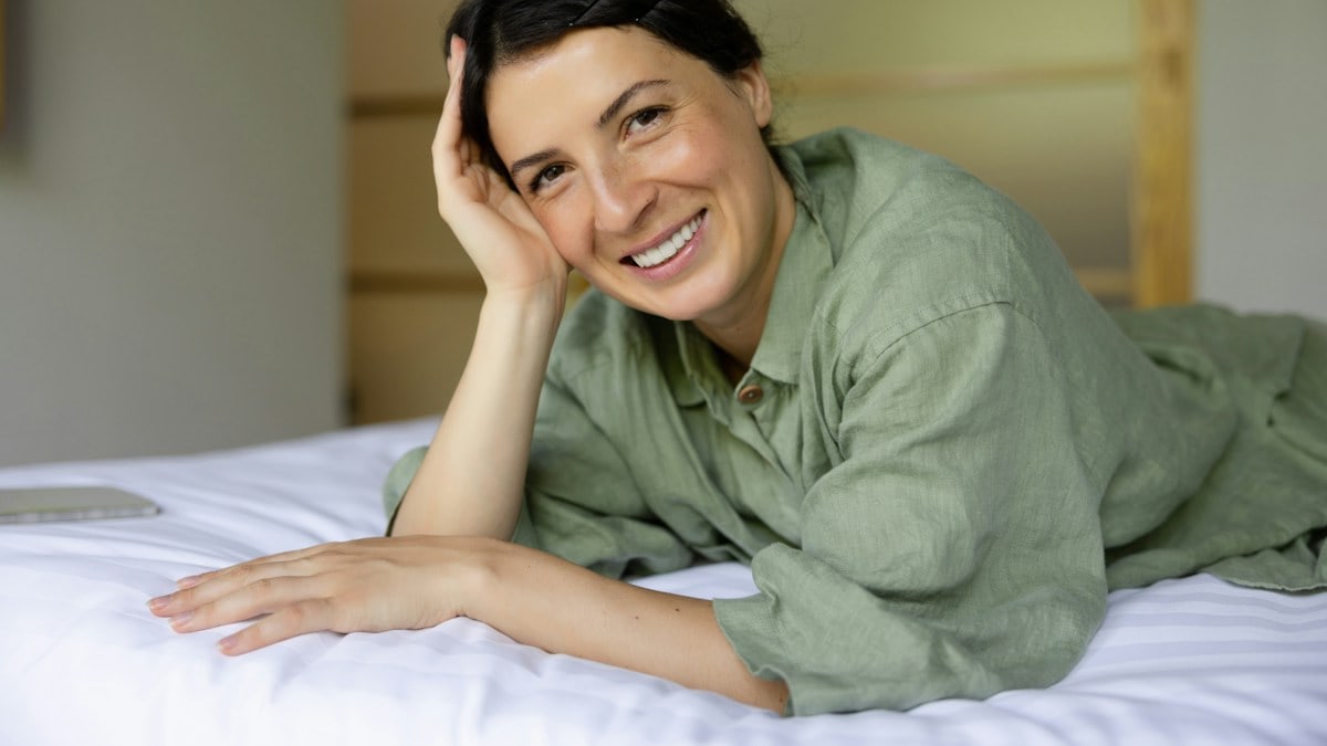 a woman laying on top of a bed next to a laptop computer